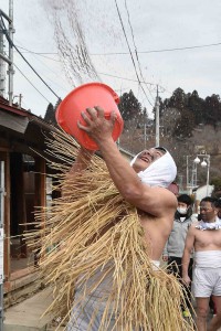 Men in straw costume throwing water over houses