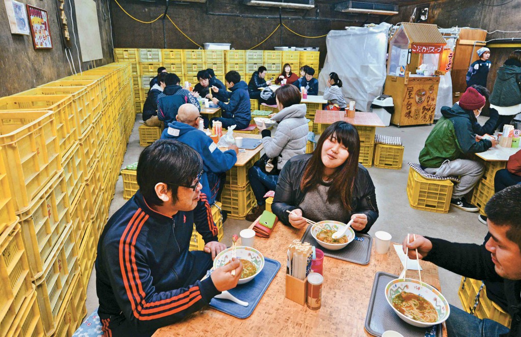 People enjoying ramen noodles surrounded by piles of plastic crates (in Katsuragi-cho, Wakayama Prefecture)