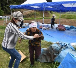 An elderly evacuee being assisted on her way to evacuation center (in Nishihara-mura, Kumamoto Prefecture)