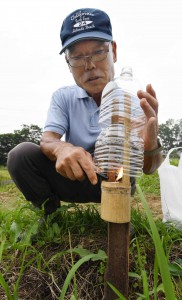 Member of Yokoze-machi Terasaka Stepped Rice Preservation Association lighting candles. Candles are covered by plastic bottles as rain hood.