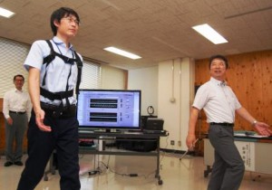 In front of a computer of data display, Akira Ichikawa (right), Chief Engineer of Saku Central Hospital, is providing a patient wearing a sensing device with guidance on how to walk with a proper posture. (Saku-shi Nagano prefecture)