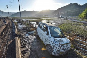 A car covered with mud is seen on Wednesday, Aug. 31, on a sidewalk along the rice paddies in the town of Iwaizumi, Iwate Prefecture, after it was washed away by a flood.