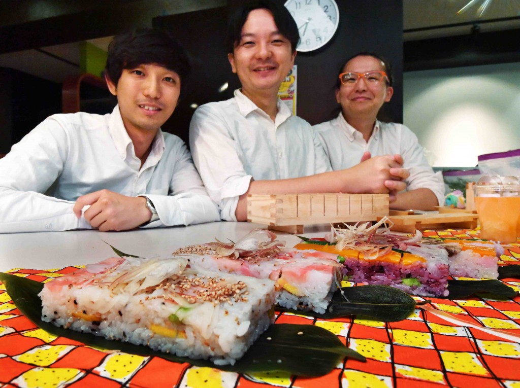 (From left) Jun Okubo, Sogen Ichizumi and Keita Nakagawa, members of Hoxai Kitchen, pose for a photo in front of vegesushi served on bamboo leaves in Tokyo’s Shinjuku Ward.