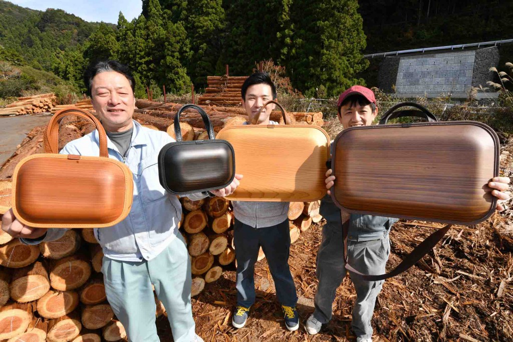 Workers of Ecoasu in Umaji, Kochi Prefecture, show wooden bags in various designs and sizes in front of cedar logs.