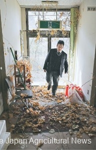 Tanaka entering the former JA Futaba Northern Farming Center. Dry leaves were covering the floor. (in Futaba Town, Fukushima Prefecture)