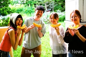 Participants smiling, holding slices of Yubari Melon (in Yubari City, Hokkaido, photo provided by JA Yubari City)
