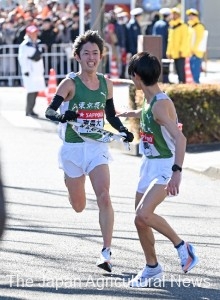 Kanno (left) completed the 9th leg run and handed over the sash to the 10th leg runner. (On January 3 in Tsurumi Ward, Yokohama City)